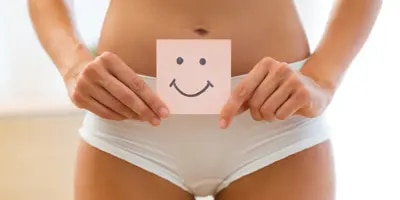 Femme en culotte blanche tenant un papier avec un smiley souriant dessus