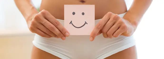 Femme en culotte blanche tenant un papier avec un smiley souriant dessus