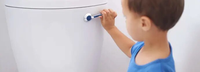 Un petit garçon en train de tirer la chasse d'eau des toilettes