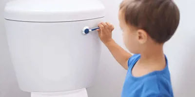 Un petit garçon en train de tirer la chasse d'eau des toilettes