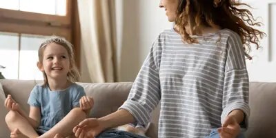 Femme et enfant assis en position de méditation sur un canapé.