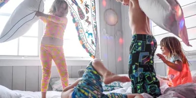 4 enfants faisant une bataille de polochons lors d'une soirée pyjama