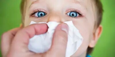 Enfant qui se fait couvrir le nez d'un mouchoir.