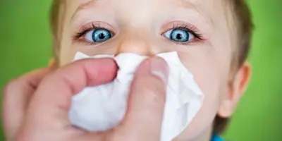Enfant qui se fait couvrir le nez d'un mouchoir.
