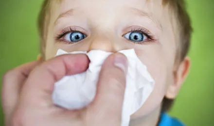 Enfant qui se fait couvrir le nez d'un mouchoir.