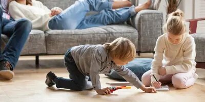 La famille se détend dans le salon, les enfants jouent par terre.