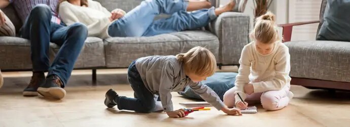 La famille se détend dans le salon, les enfants jouent par terre.