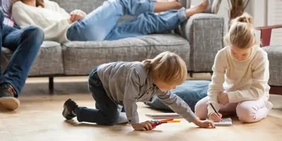 La famille se détend dans le salon, les enfants jouent par terre.