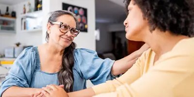 Une personne aux cheveux bouclés sourit tout en engageant une conversation.
