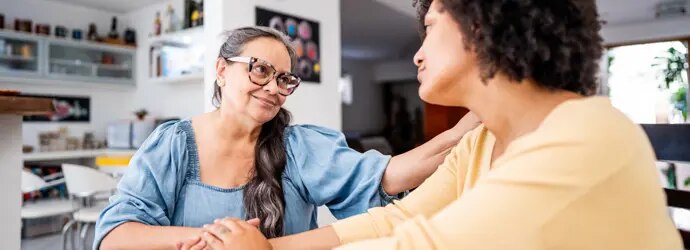 Une personne aux cheveux bouclés sourit tout en engageant une conversation.