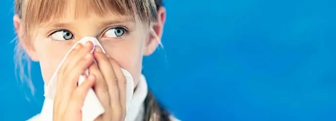 Flunssainen tyttö pitelee paperinenäliinaa nenänsä edessä