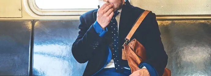 Pukumies istuu junassa ja niistää nenäänsä