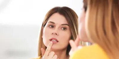 Femme traite un bouton de fièvre devant le miroir