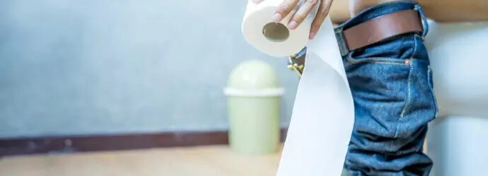Femme dans les toilettes qui montre comment utiliser moins de papier toilette