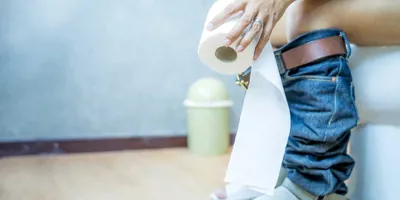 Femme dans les toilettes qui montre comment utiliser moins de papier toilette