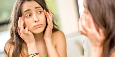 Un adolescent vérifie ses yeux gonflés par les allergies dans le miroir