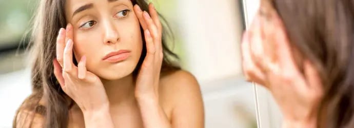 Un adolescent vérifie ses yeux gonflés par les allergies dans le miroir