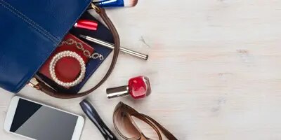 Le sac d'une femme sur un bureau en bois avec son contenu qui déborde 