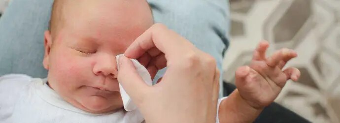 Des parents nettoient les yeux d'un bébé