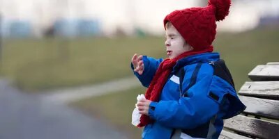 Une enfant éternue sur un banc dans un parc en hiver