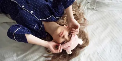 Un enfant dans son lit avec un masque pour les yeux a le nez bouché