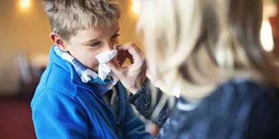 Une mère mouche le nez de son enfant et peut se demander ce qu'il faut faire pour éviter la propagation du rhume