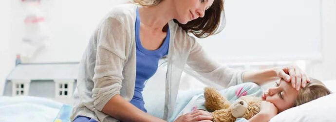 Une mère s'occupe de sa fille dans son lit avec un rhume