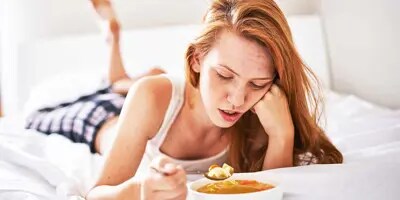 Femme au lit avec un bol de soupe ne veut pas manger