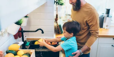 Äiti auttaa lapsiaan pesemään kädet keittiössä