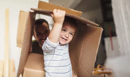 Un petit garçon tient une boîte en carton pendant un déménagement avec sa famille