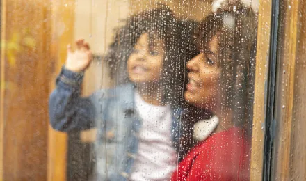Mère et enfant regardant la pluie à travers la fenêtre