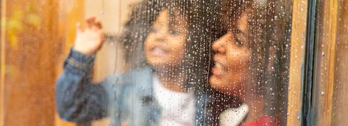 Mère et enfant regardant la pluie à travers la fenêtre