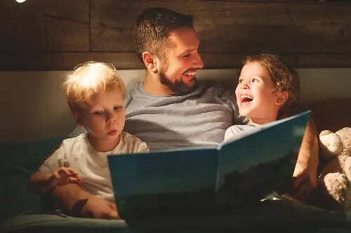 Un homme fait la lecture à deux jeunes enfants dans leur lit. L&#x27;un des enfants et l&#x27;homme sourient.