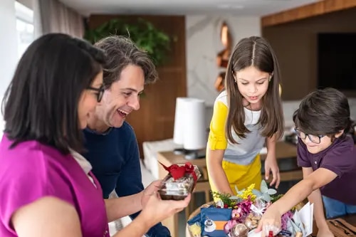 Deux adultes et deux enfants ouvrent un panier de nourriture en souriant et en inspectant les produits.