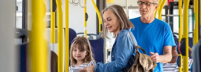 Famille avec enfant montant dans un bus, rails jaunes.