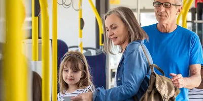 Famille avec enfant montant dans un bus, rails jaunes.