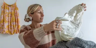 Nainen pitää kädessään beigeä vaatekappaletta ja tutkii sitä tarkasti