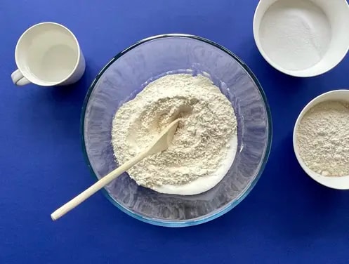 Enfants riant dans des chapeaux de chef cuisant et faisant un gâchis dans la cuisine