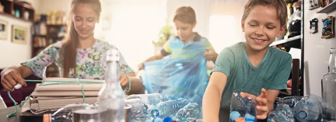 Lapset lajittelevat muovipulloja kierrätystä varten kotona