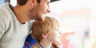 Un homme et un garçon regardent par la fenêtre d'un bus en montrant du doigt des sites touristiques.