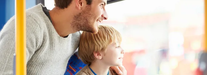 Un homme et un garçon regardent par la fenêtre d'un bus en montrant du doigt des sites touristiques.