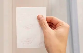 Une personne tient un rouleau de papier hygiénique devant elle, on ne voit que sa main.