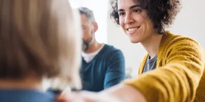 Femme souriant à quelqu'un, assis à une table.