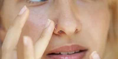 Femme touchant son piercing au nez